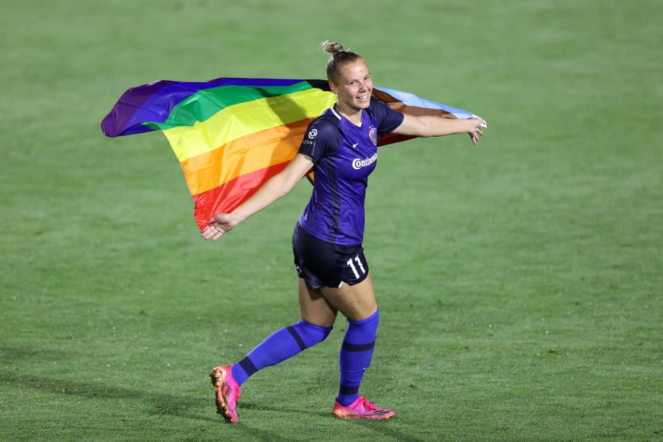 Courage forward Merritt Mathias poses with a rainbow Pride flag after a game against the Portland Thorns on North Carolina's 2021 Pride night.