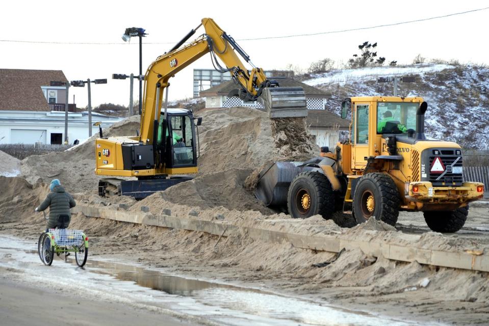 A cyclist rides past heavy equipement clearing sand from around Atlantic Avenue near the Westerly Town beach along the Misquamicut coast after a recent storm washed out dunes along the beaches.