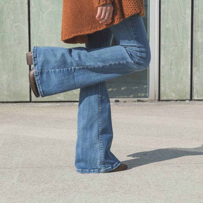 Woman in blue jeans standing on one foot on a cement floor