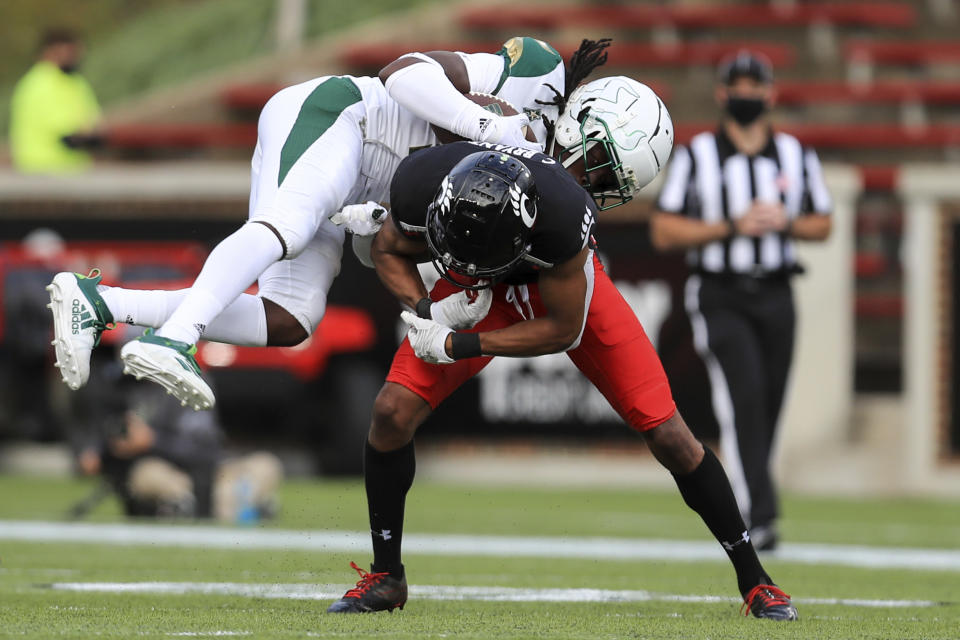 South Florida wide receiver Randall St. Felix, top, makes a catch and is upended by Cincinnati cornerback Coby Bryant, bottom, during the second half of an NCAA college football game, Saturday, Oct. 3, 2020, in Cincinnati. (AP Photo/Aaron Doster)