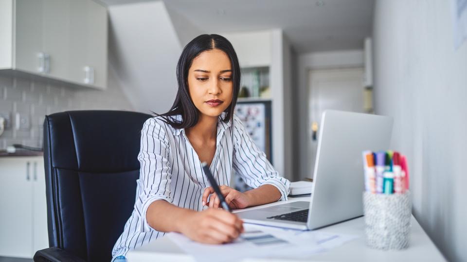 Cropped shot of an attractive young businesswoman sitting alone and calculating her finances while at home alone.