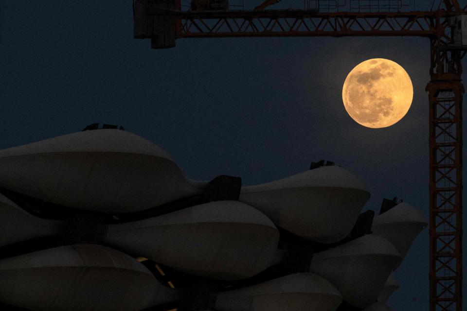 The full moon (pink moon) rises behind the Basra International Stadium, in Iraq's southern city, on April 16, 2022.