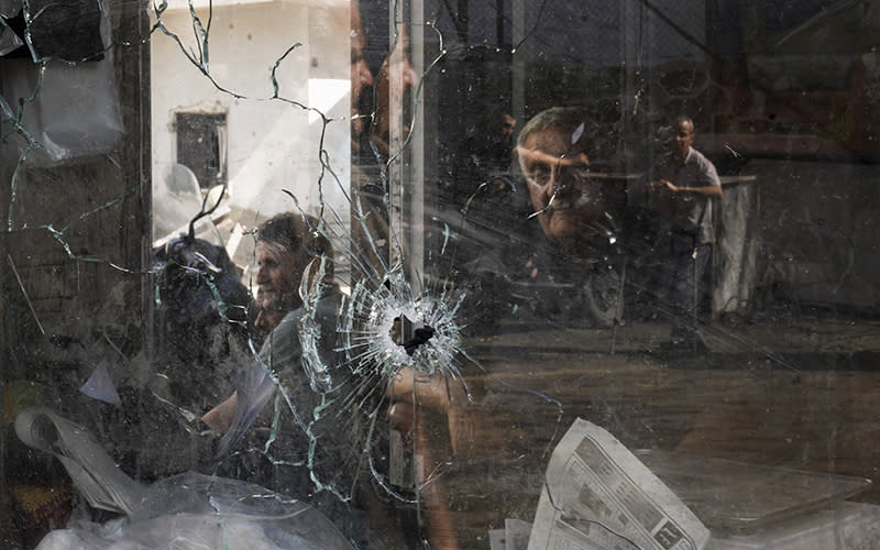 A bullet hole is seen in a shop window following an Israeli military raid in the Jenin refugee camp, West Bank. Through the glass can be seen several people.