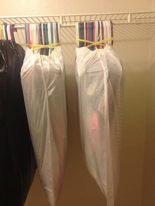 garbage bags pulled up around a dozen or so hangers with clothes on them