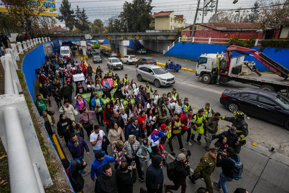 Camila Gómez, madre de Tomás Ross, de 5 años, que padece distrofia muscular de Duchenne, está acompañada por simpatizantes cuando llega a pie a Santiago, Chile, después de caminar durante aproximadamente un mes para recaudar fondos para el tratamiento de su hijo en la madrugada del miércoles 29 de mayo de 2024. (AP Foto/Esteban Félix)