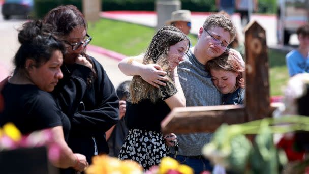 PHOTO: Jenni Seeley, Dakota Britvich, and Abbi Boyd hug as they visit a memorial set up near the scene of a mass shooting at the Allen Premium Outlets mall on May 8, 2023 in Allen, Texas. (Joe Raedle/Getty Images)