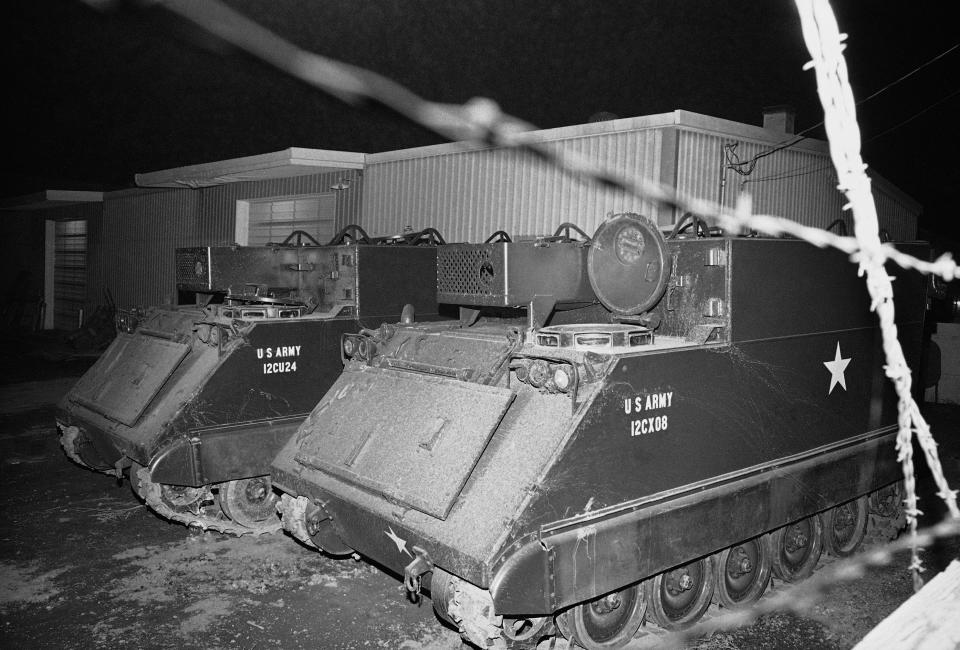 FILE - Two armored personnel carriers wait in the darkness near the Bureau of Indian Affairs headquarters in Wounded Knee, S.D., on Feb. 28, 1973. (AP Photo, File)