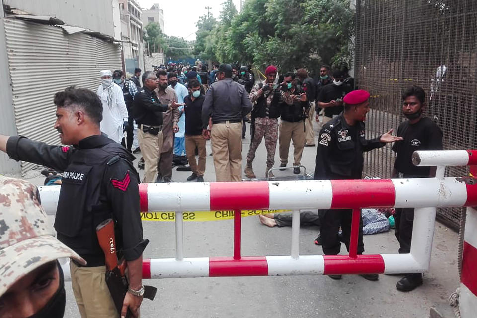 Policemen secure an area around a body outside the Pakistan Stock Exchange building after a group of gunmen attacked the building in Karachi on June 29, 2020. - A group of gunmen attacked the Pakistan Stock Exchange in Karachi on June 29, according to police and officials from the trading floor. (Photo by Asif HASSAN / AFP) (Photo by ASIF HASSAN/AFP via Getty Images)