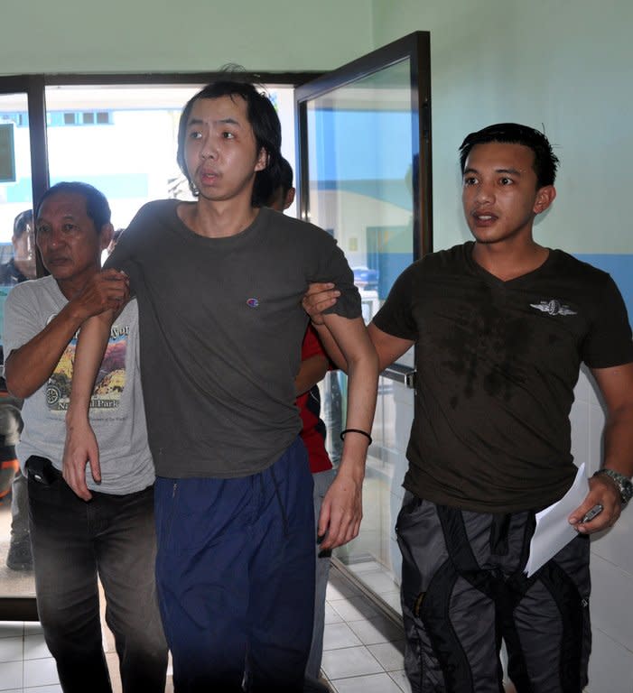 Tung Wei Jie (C), a plantation worker held hostage by Philippine Muslim extremists for almost a year, is escorted by police in Jolo on August 6, 2013. Tung told local media that he escaped in heavy rain from a bamboo hut in the jungle when his abductors went for pre-dawn prayers