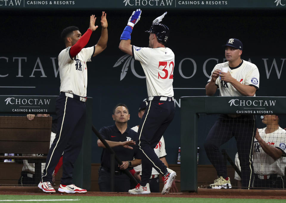 Texas Rangers' Marcus Semien, left, greets Evan Carter (32) at the dugout after Carter's home run against the Cincinnati Reds during the second inning of a baseball game Friday, April 26, 2024, in Arlington, Texas. (AP Photo/Richard W. Rodriguez)