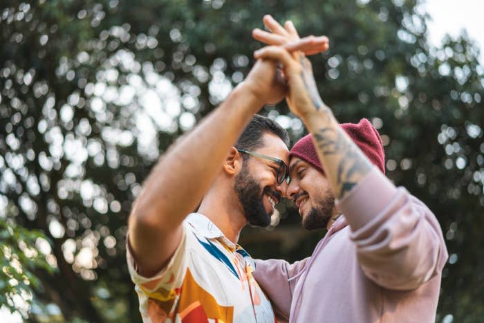 A couple holding hands and putting their foreheads together while they're outside