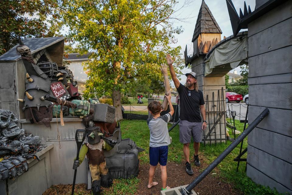 Bud Hasert high-fives his son, Henry, 10, as Henry carries a fake arm outside their home Oct. 24 in southwest Austin.