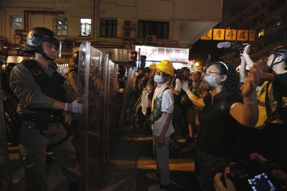 Protesters face off riot police officers in Hong Kong, Sunday, July 21, 2019. Protesters in Hong Kong pressed on Sunday past the designated end point for a march in which tens of thousands repeated demands for direct elections in the Chinese territory and an independent investigation into police tactics used in previous demonstrations. (AP Photo/Bobby Yip)