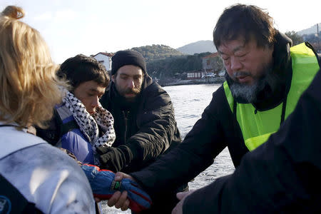 Chinese artist Ai Weiwei (R) helps an Afghan migrant as he arrives with other refugees and migrants on a raft on the Greek island of Lesbos, January 25, 2016. REUTERS/Giorgos Moutafis/File Photo