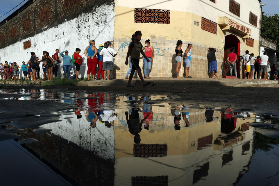 Vecinos en fila para recibir alimentos básicos gratuitos ante la escuela primaria de Santa Ana, en Asunción, Paraguay, proporcionados por un programa del Ministerio de Educación, durante las cuarentenas contra el COVID-19, el martes 31 de marzo de 2020. (AP Foto/Jorge Sáenz)