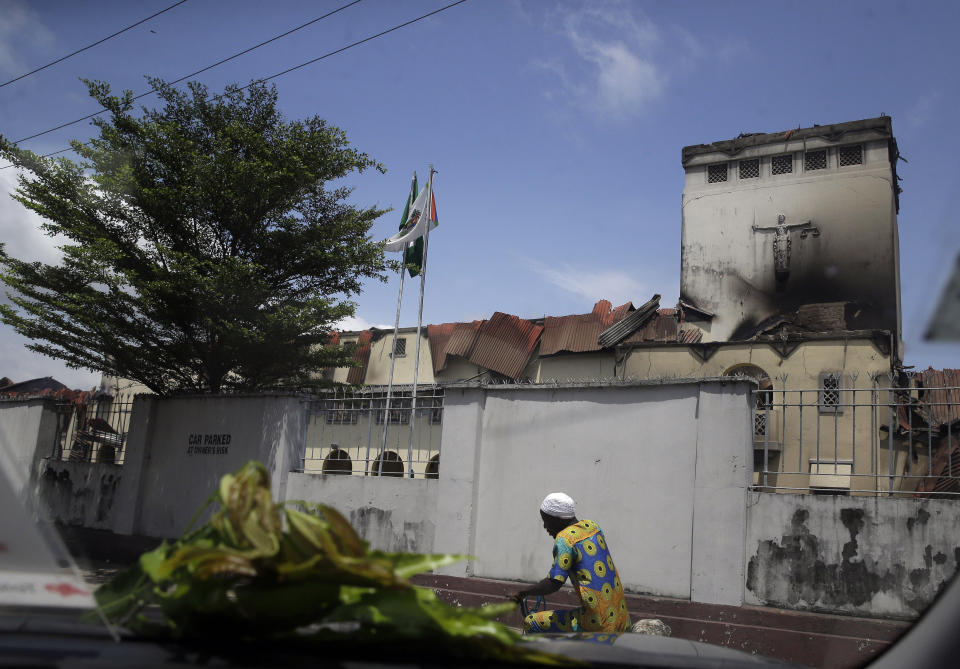 A man rides a bicycle past a burnt Court of Appeal building in Lagos, Nigeria, Thursday Oct. 22, 2020. Lagos streets were empty and shops were shuttered Thursday, as residents of Nigeria's largest city obeyed the government's curfew, stopping the protests against police brutality that had lasted for two weeks. ( AP Photo/Sunday Alamba)