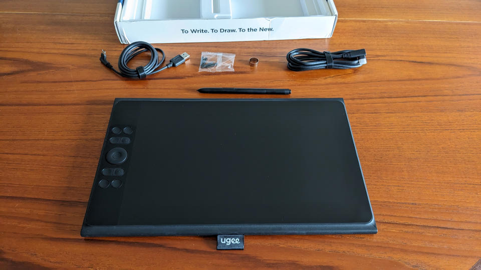 Ugee UE12 Plus review; a drawing tablet on a wooden table with cables and a stylus