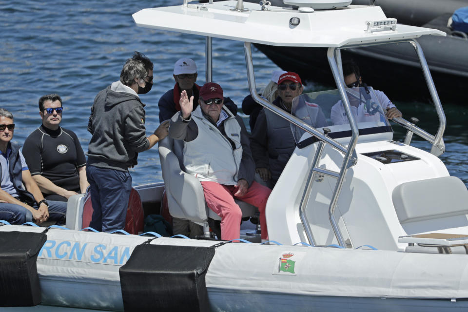 Spain's former King Juan Carlos, centre, waves from a support launch that will accompany the Bribon yacht during a 'regatta' race between yachts in Sanxenxo, north western Spain, Friday, May 20, 2022. Spain's former King has returned to Spain for his first visit since leaving nearly two years ago amid a cloud of financial scandals. (AP Photo/Lalo R. Villar)