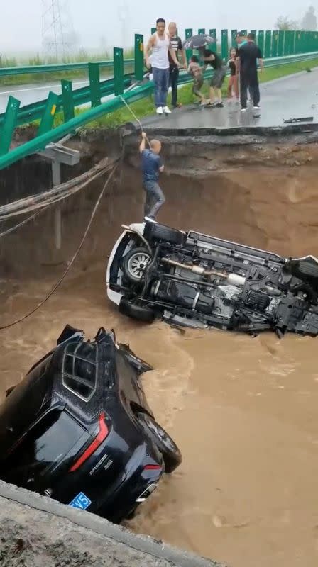 A man stands on a car that fell off the collapsed bridge in Shangzhi