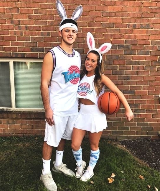 A couple wearing Tune Squad jersey's while wearing bunny ears