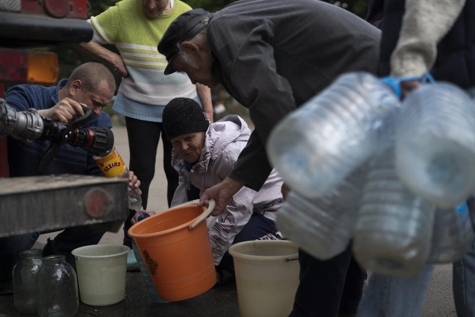 People gather to fill cans with water from a firefighters truck in Lysychansk, Luhansk region, Ukraine, Friday, May 13, 2022. (AP Photo/Leo Correa)