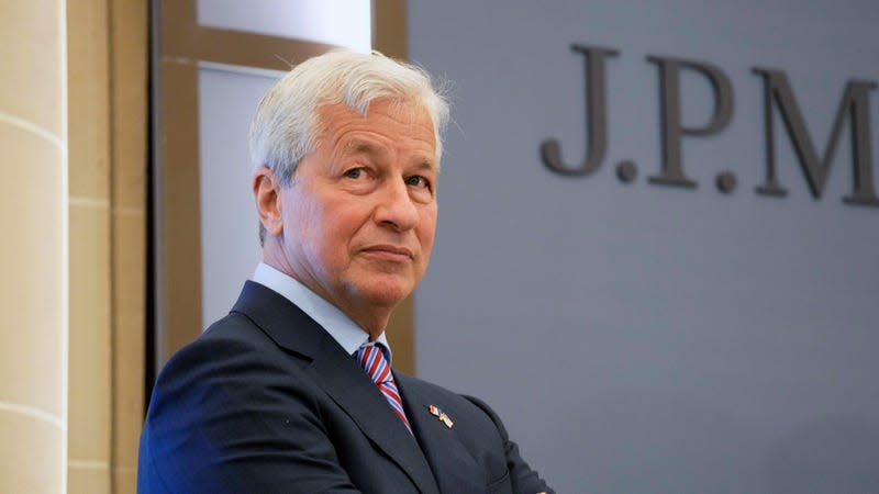 Jamie Dimon stands in front of a door with a JPMorgan sign on it