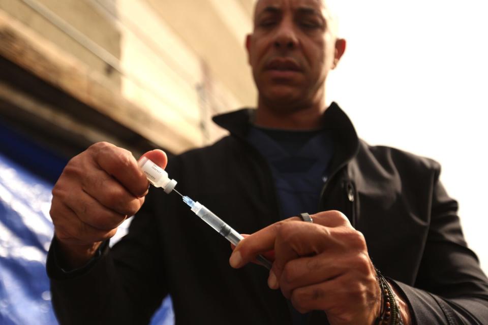 Closeup of a man filling a syringe from a vial.
