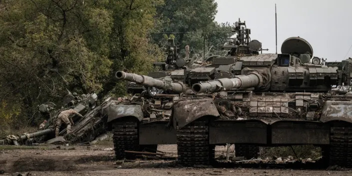 Ukrainian soldiers (L) scavenge an abandoned Russian T-90A tank in Kyrylivka, in the recently retaken area near Kharkiv, on September 30, 2022.