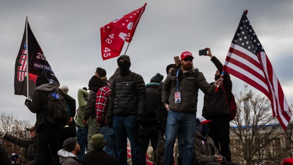 A group of pro-Trump protesters wave flags while standing on an armored police vehicle on the grounds of the Capitol Building on Jan. 6, where the mob stormed, breaking windows and clashing with police officers. (Photo by Jon Cherry/Getty Images)