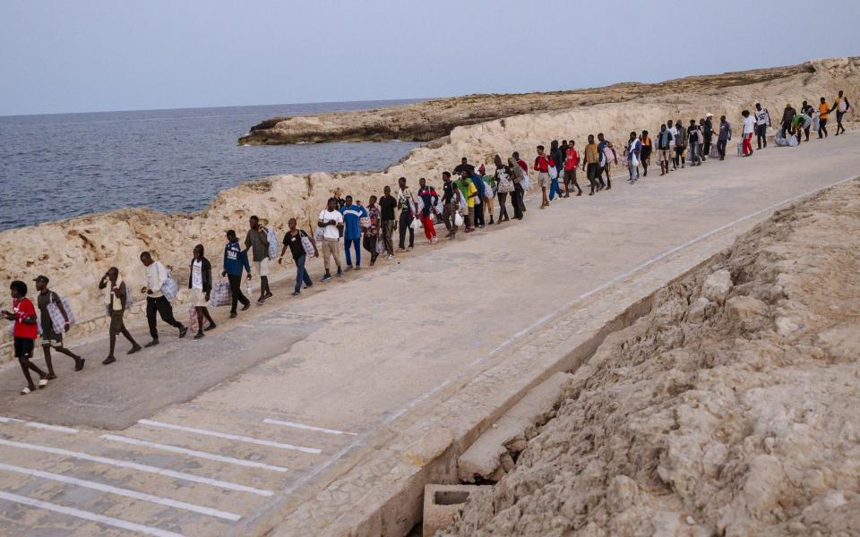 Migrants in Lampedusa make their way to a ferry to be taken to the Italian mainland