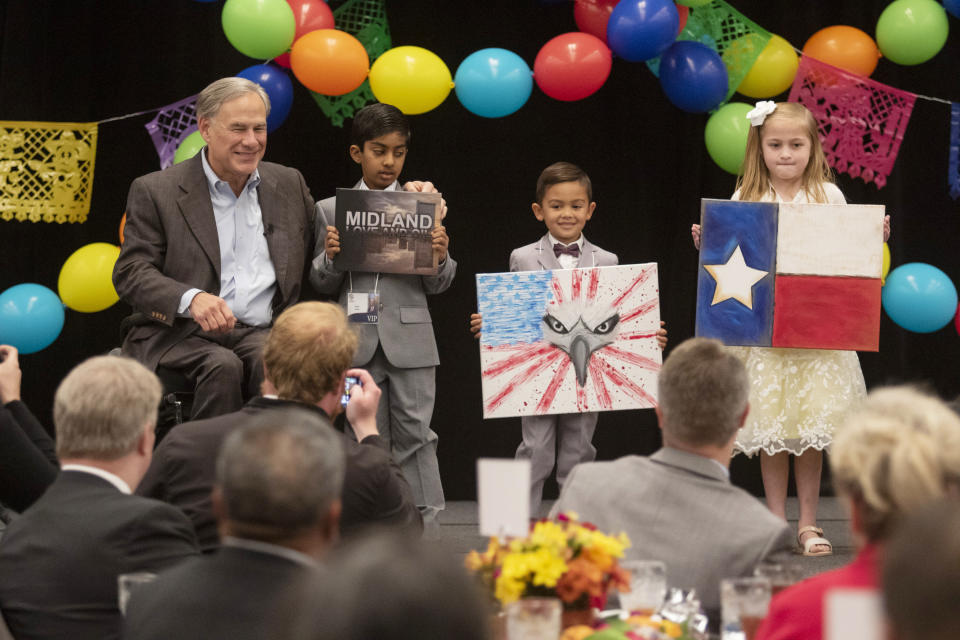 Gov. Greg Abbott, left, smiles after receiving gifts at the Midland Chapter of the Republican National Hispanic Assembly's Reagan Lunch at the Bush Convention Center Friday, Nov. 5, 2021, in Midland, Texas. (Jacob Ford/Odessa American via AP)