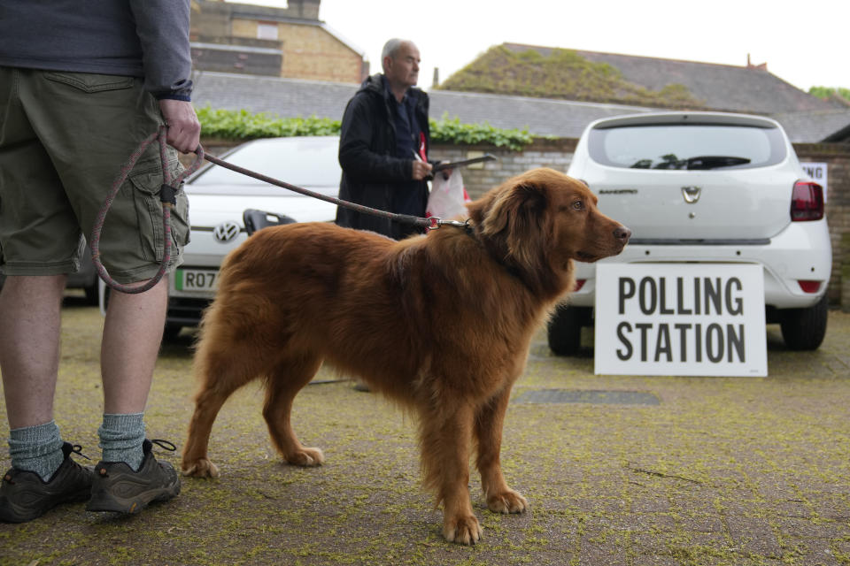 A voter waits with his dog outside a polling station as it opens for people to vote in London, Thursday, May 2, 2024. London Mayor Sadiq Khan, is seeking re-election, and standing against 12 other candidates for the post of Mayor of London. There are other Mayoral elections in English cities and as well as local council elections. (AP Photo/Kin Cheung)