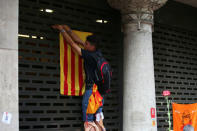 A protester hangs an Estelada (Catalan separatist flag) in a building outside the Catalan region's economy ministry building after junior economy minister Josep Maria Jove was arrested by Spanish police during a raid on several government offices, in Barcelona, Spain, September 20, 2017. REUTERS/Albert Gea