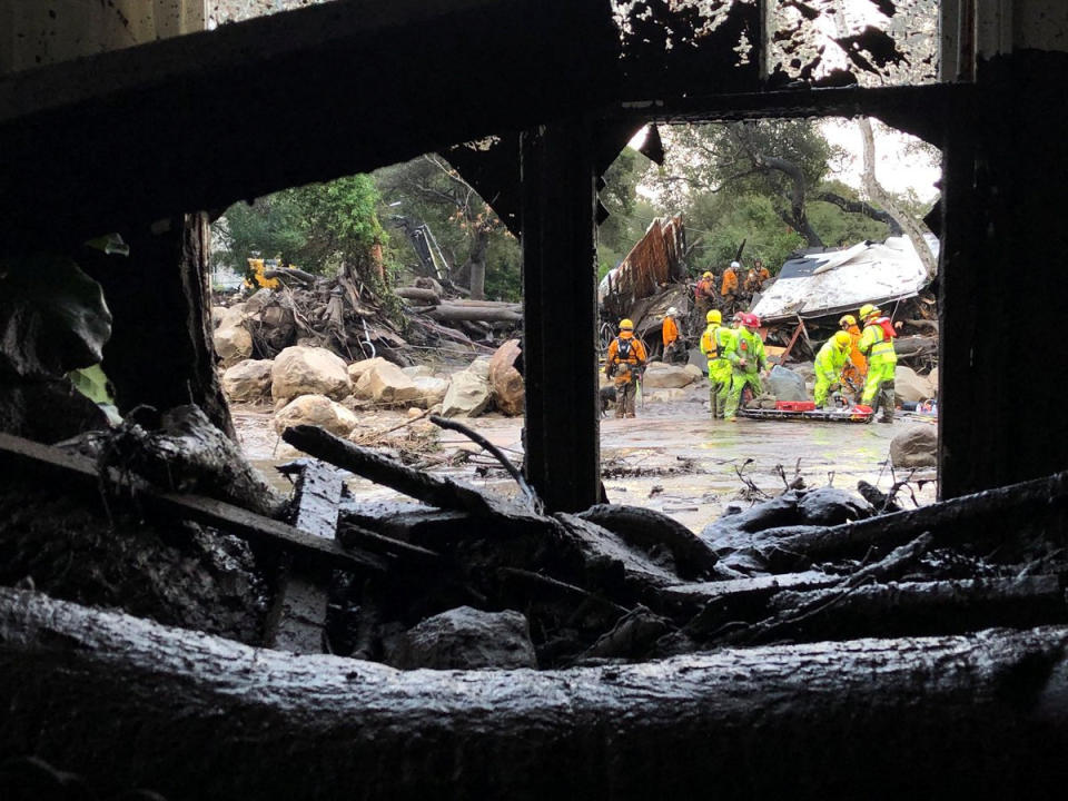 Emergency personnel search through debris and damaged homes.