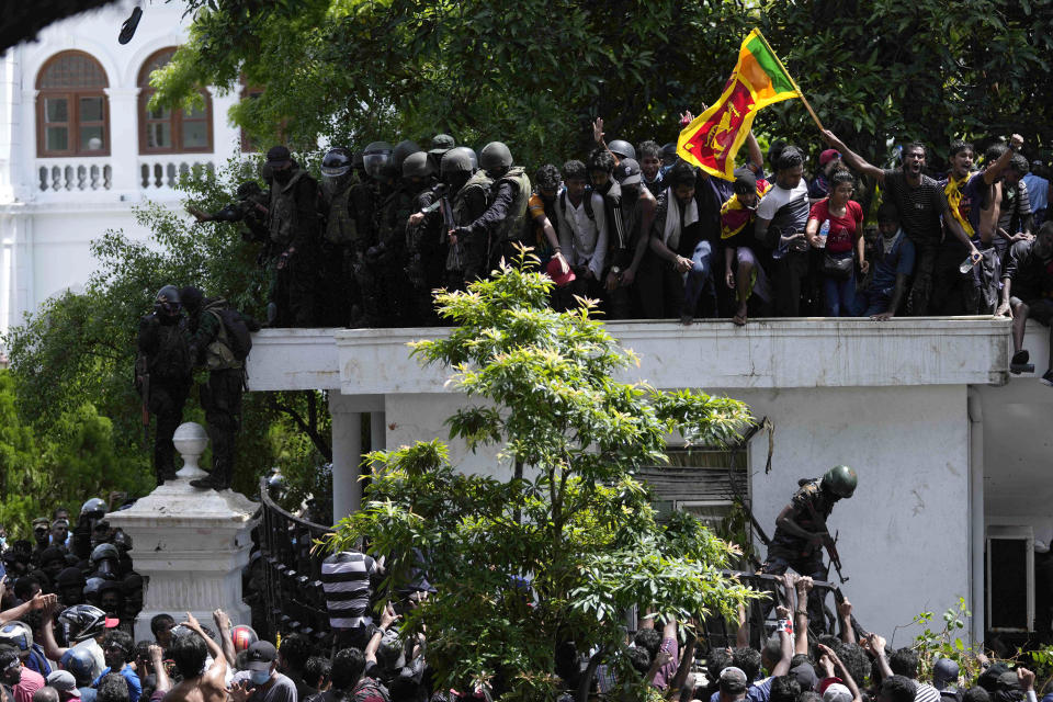 Protesters, one carrying national flag, storm the Sri Lankan Prime Minister Ranil Wickremesinghe's office, demanding he resign after president Gotabaya Rajapaksa fled the country amid economic crisis in Colombo, Sri Lanka, Wednesday, July 13, 2022. Rajapaksa fled on a military jet on Wednesday after angry protesters seized his home and office, and appointed Prime Minister Ranil Wickremesinghe as acting president while he is overseas. Wickremesinghe quickly declared a nationwide state of emergency to counter swelling protests over the country's economic and political collapse. (AP Photo/Eranga Jayawardena)