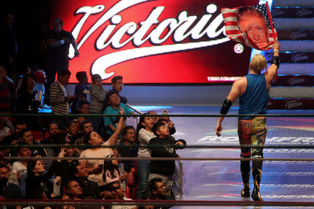 U.S. wrestler Sam Adonis, 27, role-playing as a fan of U.S. President Donald Trump, waves a flag with Trump's face as he is booed by the spectators after a wrestling fight at the Coliseo Arena in Mexico City, Mexico, February 12, 2017. REUTERS/Edgard Garrido