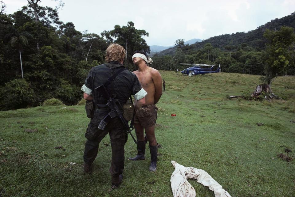 <div class="inline-image__caption"><p>A DEA agent stands with a blindfolded prisoner following a raid on a cocaine lab in the Peruvian jungle.</p></div> <div class="inline-image__credit">Gregory Smith/Corbis via Getty Images</div>