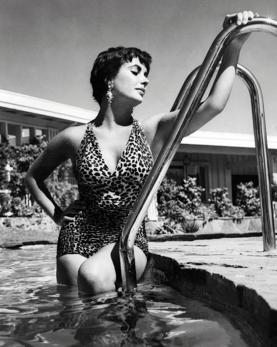 Wearing a one-piece leopard print swimsuit, circa 1955.