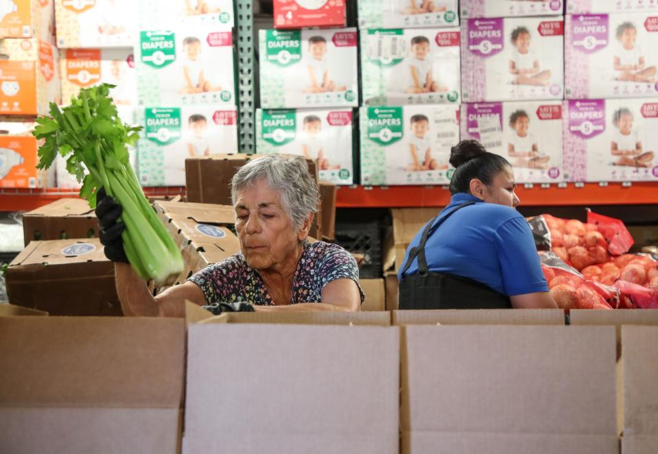 Volunteer Gloria Kelly packs food boxes for distribution at the Galilee Center in Mecca, Calif., August 17, 2023.