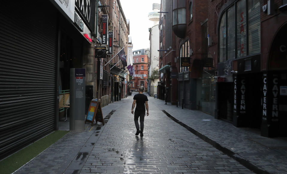 FILE - In this Oct. 14, 2020 file photo, a lone man walks, past the famous Cavern club and other closed pubs and bars as new anti-coronavirus measures are set to come into force in Liverpool, England. Hundreds of thousands of jobs in Britain hang in the balance as employers try to plot their way through a resurgence of the coronavirus without the backstop of a national salary support program. (AP Photo/Frank Augstein, file)