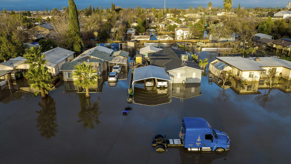 Following days of rain, floodwaters surround homes and vehicles in the Planada community of Merced County, Calif., on Tuesday, Jan. 10, 2023. (AP Photo/Noah Berger)