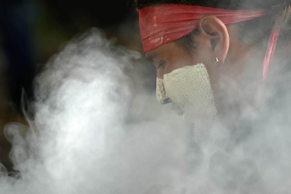 Aboriginal man Josh Sly of the Muggera Dancers prepares a fire for a smoking ceremony at the start of an Invasion Day rally in Sydney, Thursday, Jan. 26, 2023. Australia is marking the anniversary of British colonists settling modern day Sydney in 1788 while Indigenous protesters deride Australia Day as Invasion Day. (AP Photo/Rick Rycroft)