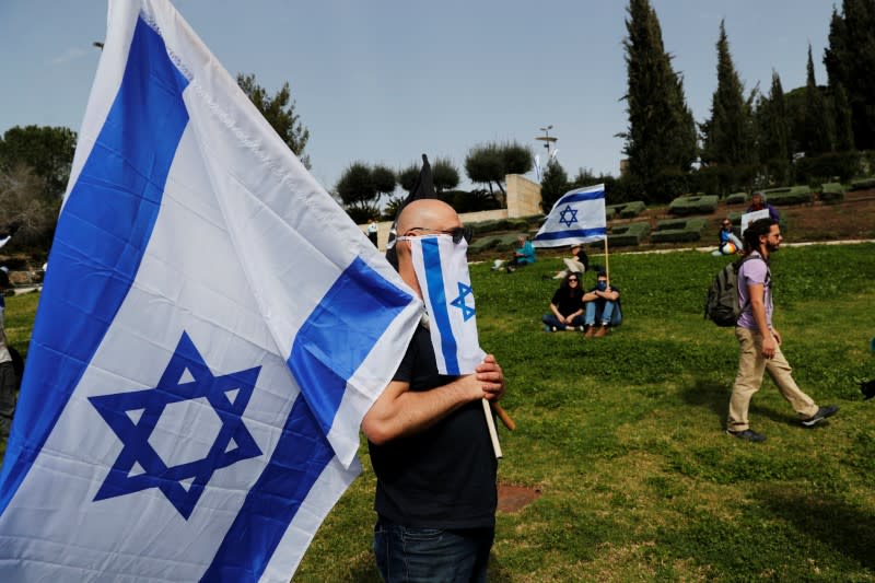 Israelis hold national flags during a demonstration against PM Netanyahu's caretaker government, in Jerusalem