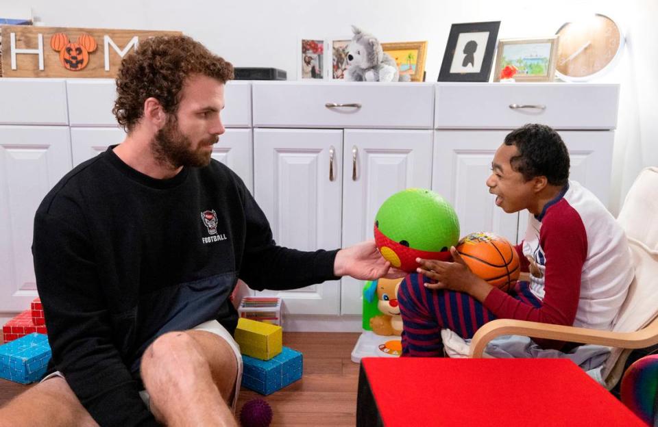 Grayson Ketchie plays ball with N.C. State linebacker Payton Wilson at Grayson’s home in Garner Wednesday, Oct. 18, 2023. Ketchie, 12, has been suffering from severe neurological issues since he was a baby. He has been a Wolfpack fan since he was three and the players made a surprise visit to his home that evening.