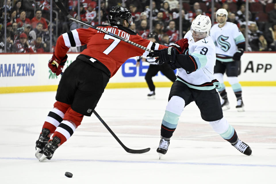 Seattle Kraken center Ryan Donato (9) shoots as he is checked by New Jersey Devils defenseman Dougie Hamilton (7) during the first period of an NHL hockey game Thursday, Feb. 9, 2023, in Newark, N.J. (AP Photo/Bill Kostroun)