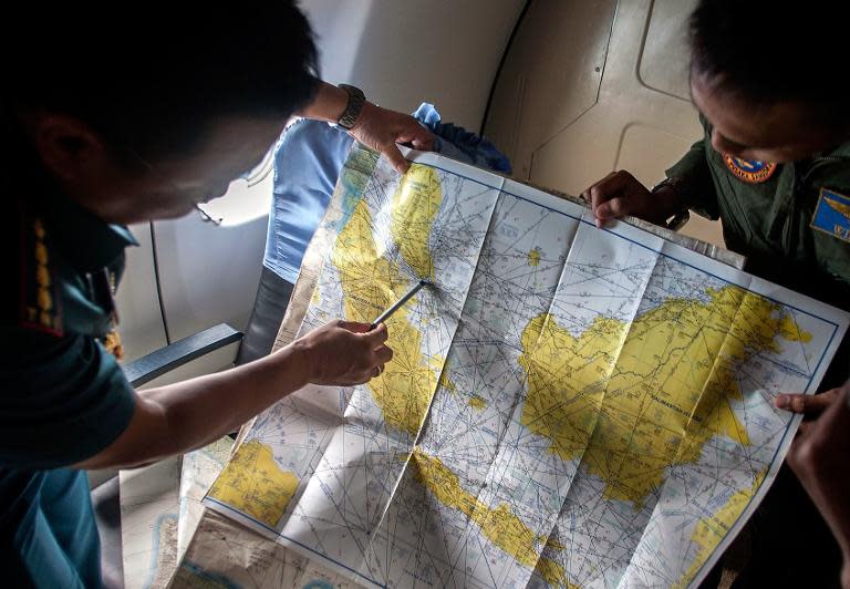 Indonesian army personnel read a map during a search and rescue (SAR) operation for missing Malaysian air carrier AirAsia flight QZ8501, over the waters of the Java Sea on December 29, 2014