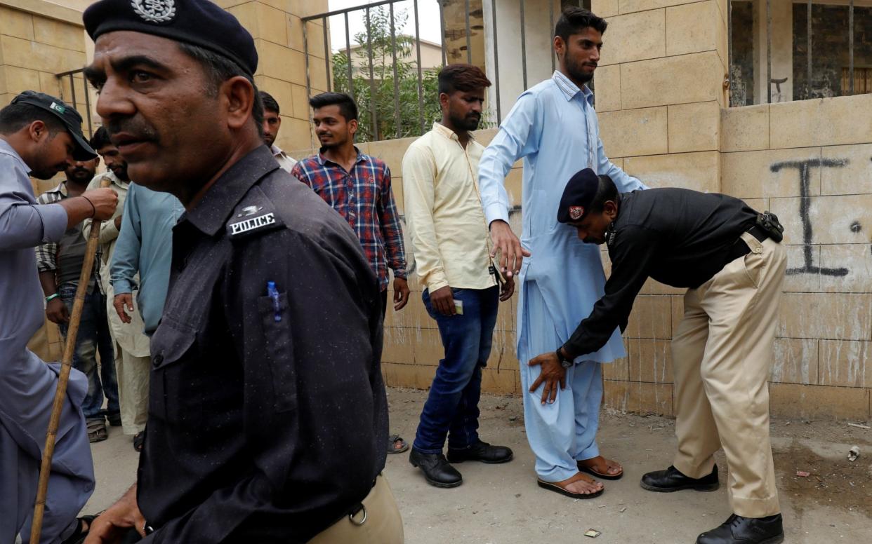 A police officer checks mock voters while other looks on, as they perform a rehearsal for security measures, outside a polling booth, ahead of general elections in Karachi, Pakistan - REUTERS