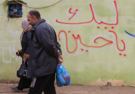 People walk past the slogan "Oh Hussein we are coming" is written on a wall in Mosul, Iraq, December 1, 2016. REUTERS/Stringer