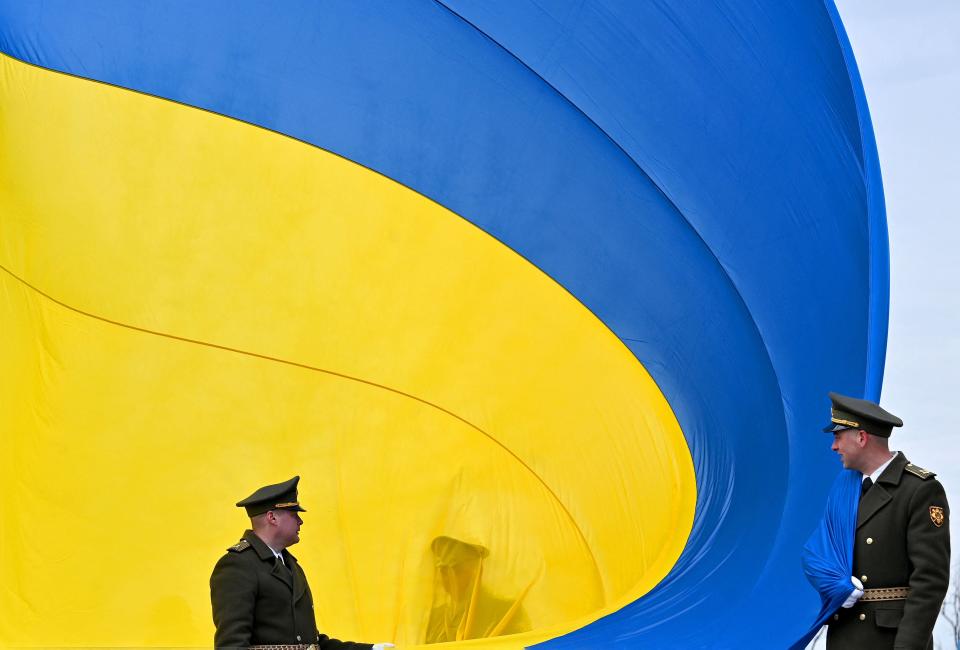 Ukrainian servicemen hold the huge national flag before it raises to the flagpole during a ceremony marking the first anniversary of the retreat of Russian troops from the Ukrainian town of Bucha (AFP via Getty Images)