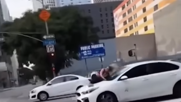 two white cars on a street woman clinging to hood